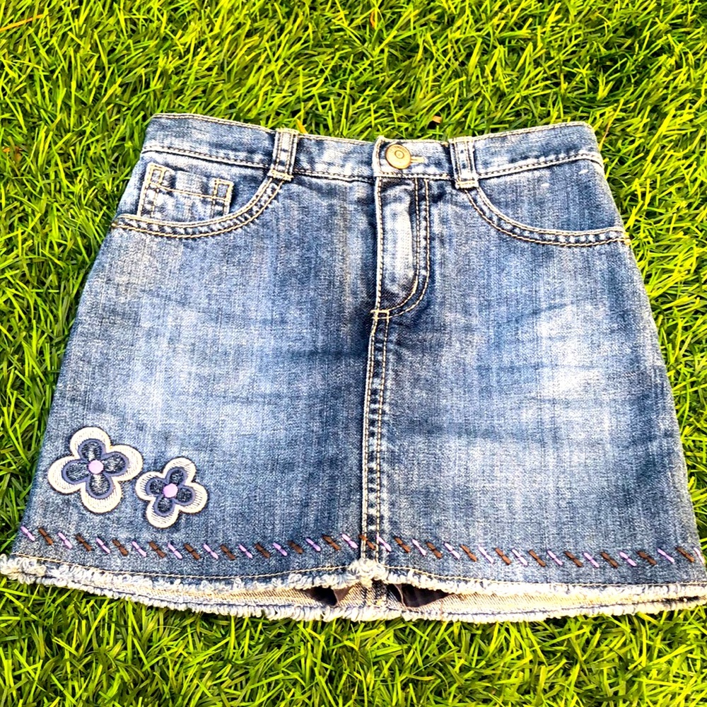 A size five jean skirt with two flower patches.